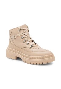 Bež nahkiseid pahkluu saapaid ümmarguse varbaga, nööbitava esiosaga, hõbedaste detailide, pehmendusega kaeluse ja nugadega kummitaldadega, millel on mustrimustrid.