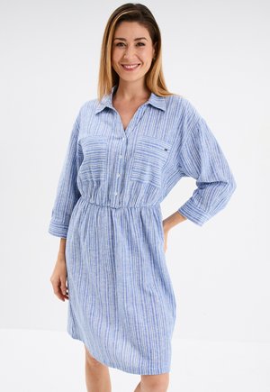 Abito camicia a righe blu con bottoni frontali, tasca sul petto e vita elastica. Realizzato in tessuto leggero con una vestibilità comoda.