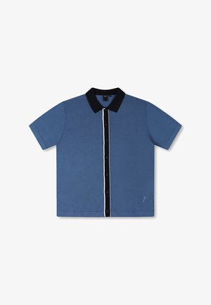 Kraukšķīgs polo krekls ar īsām piedurknēm, zils ar melnu apkakli un baltu pogu rindu. Aizmugurē ir neliels logotips kreisajā apakšējā stūrī. Gluda tekstūra.