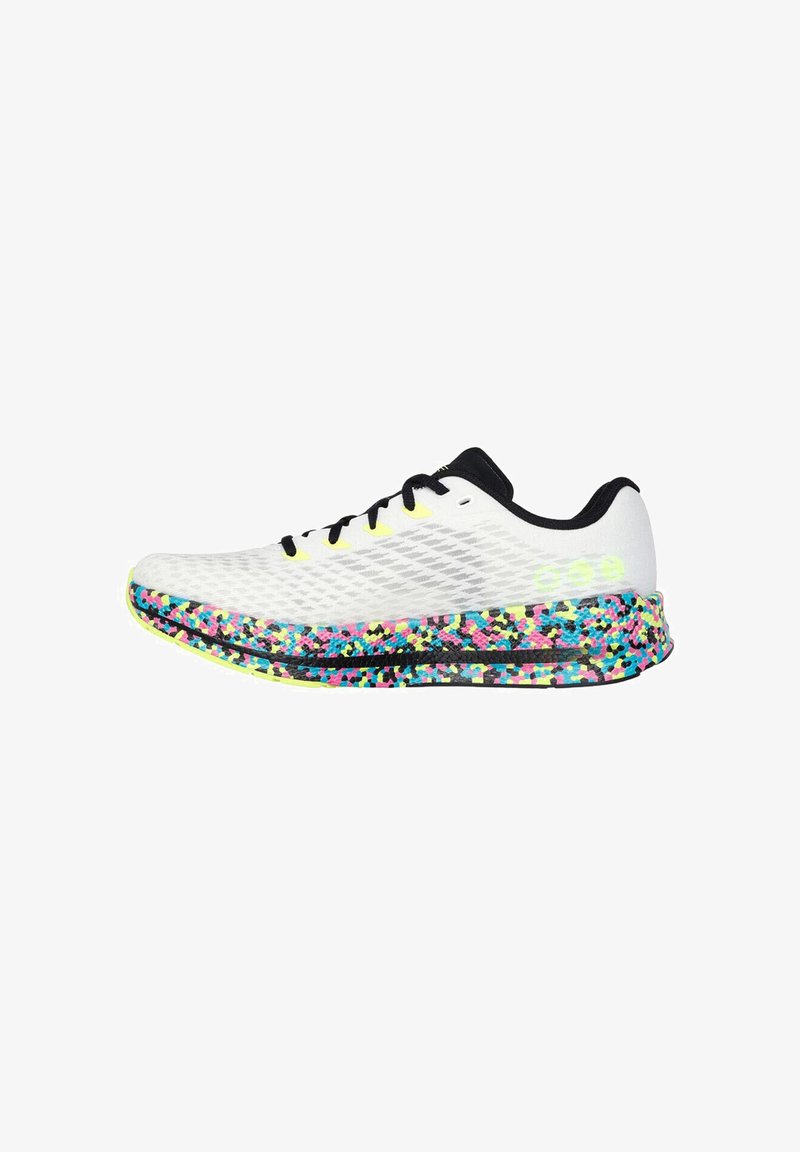 Baskets blanches avec lacets et col noirs, dotées d'une semelle mouchetée multicolore en bleu, rose, jaune et noir.