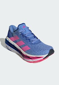 Blauwe hardloopschoen met roze accenten, ademende mesh bovenkant, текстурированные patronen, dikke witte en roze zool en een donkere neuskap.