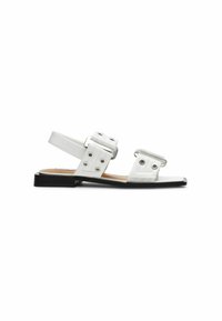 Sandalias planas blancas con correas de doble hebilla, textura suave, diseño de punta abierta y suela negra. Presenta detalles en metal plateado.