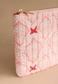 Gequilte roze pouch met witte bladpatronen en rode accenten, voorzien van een gouden rits en een gestructureerd oppervlak.