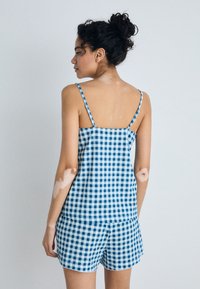 Blue and white gingham check tank top with thin straps, paired with matching shorts featuring a scalloped hem and lightweight fabric.