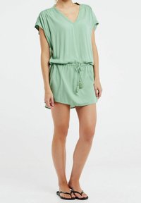 Rompers vert à manches courtes avec un col en V, taille à cordon et accents en tassel. Fabriqué à partir d'un tissu léger et lisse.