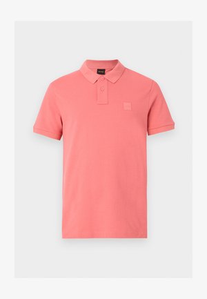 Korallroosa lühikeste varrukatega polosärk, kahe nupuga plake ning väikese reljeefse logoga vasakul rinnal.