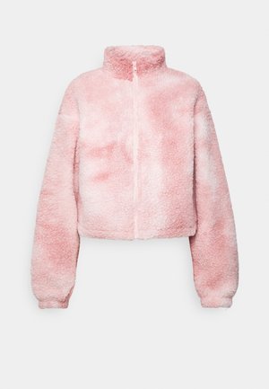 Veste polaire sherpa douce rose et blanche, manches longues, col montant et fermeture éclair frontale sur fond uni.