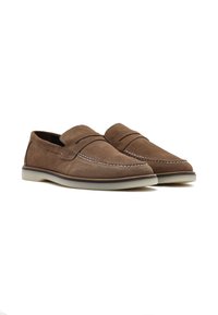 Mocassins en daim marron avec des coutures blanches contrastées, un fini en tissu doux et une semelle en caoutchouc légère. Présente un design sans lacets.
