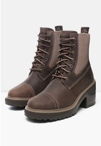 Botas de tobillo de cuero marrón con paneles elásticos en los laterales, cordones en el frente y tacones gruesos; superficie texturizada con detalles de costura y logotipo.