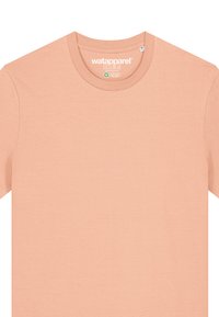 T-shirt en coton pêche clair avec un col rond, des manches courtes et une texture lisse. Présente un logo imprimé à l'intérieur du col.