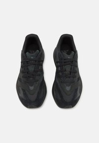 Black athletic shoes made of mesh and suede, featuring textured panels, lace closures, and a cushioned sole design.