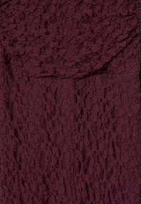 Bordeauxfarbener Spitzenstoff mit filigranen Blumenmustern, weicher Textur und geschichtetem Design. Verfügt über eine transparente Überlagerung und gewellte Kanten.