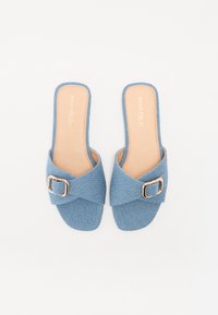 Blå tygsandaler med ett korsat remdesign och en spänne i guldton. Platt sula med en slät tanfärgad inlägg.