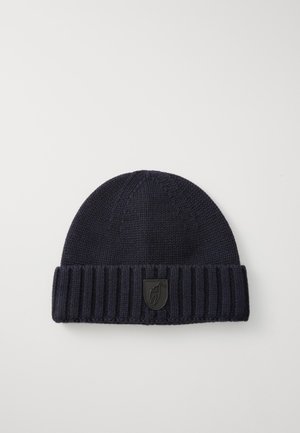 Laivaston sininen neulepipo, jossa on ribbiresori ja teksturoitu pinta. Edessä on musta logopatchi, joka tuo kontrastia yksityiskohtiin.