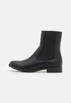 Crne kožne gležnjače s elastičnim bočnim panelima, okruglim vrhom i niskom drvenom petom za stabilnost i udobnost. Glatka tekstura.