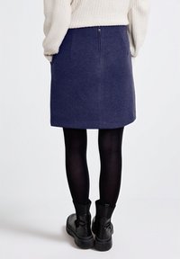 Námořnická modrá sukně s pevným, áčkovým střihem, se zipem na zadní straně. Nosit s černými punčochami a robustními černými botami.