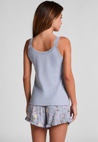 Lichtblauw geribbeld tanktop met gegolfde kanten schouderbanden, gecombineerd met bijpassende shorts met bloemenprint en een gerimpelde zoom.