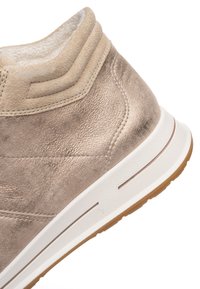 Zapatilla de caña alta de ante beige con superficie texturizada, acentos de diseño en capas y suela de goma blanca con base de tracción marrón.