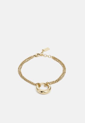 Bracciale in oro con due filamenti textured, un accento metallico circolare al centro e una chiusura con un piccolo tag.