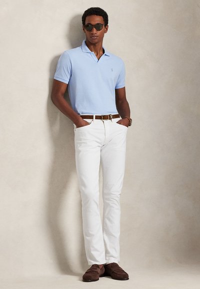 Ανοιχτό μπλε πόλο πουκάμισο, λευκά τζιν με στενή εφαρμογή, καφέ ζώνη και σκούρα σουέτ μοκασίνια. Τα γυαλιά ηλίου με σκουρόχρωμους φακούς ολοκληρώνουν το look.