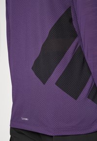 Fialová športová košeľa s textúrovanou sieťovinou, na boku so čiernym geometrickým dizajnom a s označením "CLIMACOOL" na leme.