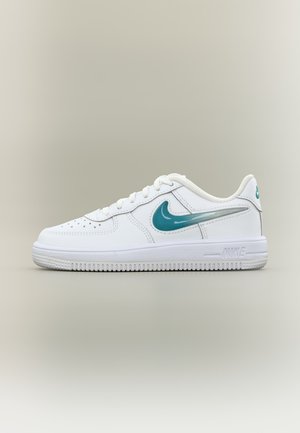 Biely teniska Nike s tyrkysovým logom Swoosh, nízky strih, perforovaná špička a biela podrážka na béžovom pozadí.
