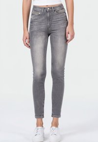 Grijze high-waisted jeans met een slim fit, voorzien van een vervaagde uitstraling, vijf zakken en opgerolde uiteinden, gecombineerd met witte sneakers.