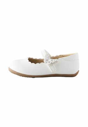 Witte meisjes Mary Jane-schoen met gekartelde randen, vlinderdetail op de band en lichtbruine rubbersole, getoond in zijaanzicht.