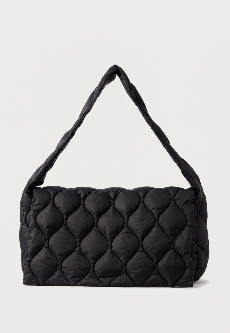 Crna torba od lijepljene tkanine s pufastom, teksturiranom površinom i jednim upletenim ručkom. Pravilnog oblika, od mekanog materijala i minimalističkog dizajna.