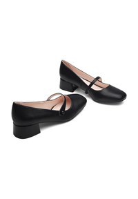 Chaussures à talons blocs en simili cuir noir avec un bout arrondi et une large sangle sur le coup de pied, présentant une texture lisse et un minimalisme dans le design.
