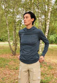 Long-sleeve hoodie in navy blue with a subtle dot pattern, made of soft material. Paired with light beige cargo pants featuring large pockets.