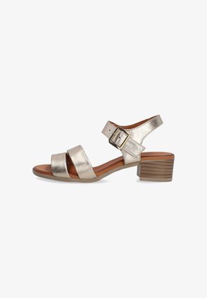 Metallic guld sandal med to brede stropper, ankelspænde og en lav stablehæl. Har en glat tekstur og en polstret indersål.