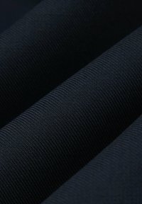 Teksturowana ciemnoniebieska tkanina z delikatnym prążkowanym wzorem. Gładka powierzchnia, widoczne złożone sekcje podkreślające głębię i warstwy.