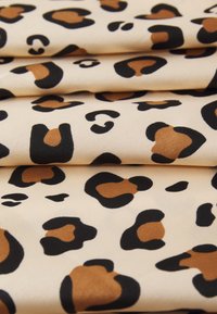 Tessuto con stampa leopardata che presenta uno sfondo crema con macchie nere e marroni. La texture è liscia e leggermente lucida.
