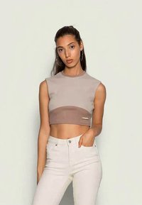 Top cropped em bege e castanho claro, com uma textura canelada e um design ajustado. Usado com jeans claros de cintura alta.