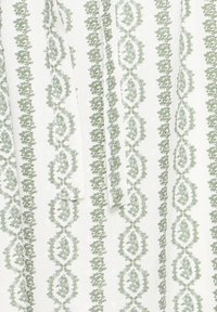 Tissu blanc avec des motifs de vigne florale verticale vert clair et un détail de ceinture en tissu nouée.