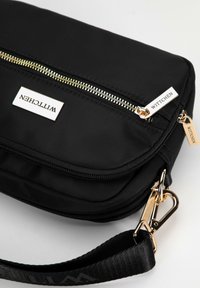 Czarna nylonowa torba na ramię z złotymi zamkami, z metką logo WITTCHEN, regulowanym paskiem i gładką teksturą.