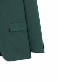 Manche de blazer texturée vert foncé et partie inférieure avant avec poche à rabat et quatre boutons noirs sur le poignet.