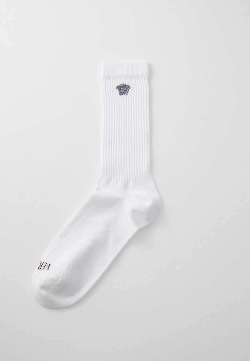 Weiße Baumwollsocken mit gerippter Textur, die ein graues Logo am Bund und dezente Markenkennzeichnung nahe der Zehenpartie aufweisen.