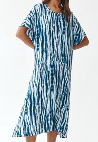 Vestido midi de estampado tie-dye en azul y blanco, con mangas cortas, un ajuste relajado y un escote redondeado. Presenta patrones verticales y circulares.