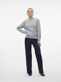 Maglione grigio lavorato a maglia con una vestibilità rilassata, polsini a coste, abbinato a jeans a gamba larga blu scuro e tacchi a punta nera.
