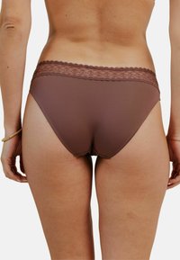 Culotte brune pour femme avec une finition en dentelle à la taille et une texture lisse. Présente une coupe classique et une couverture minimale sur les côtés.