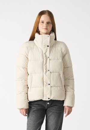 Beige pufferjack met hoge kraag, drukknoopsluiting en doorgestikte patroon. Beschikt over zijzakken en een comfortabele pasvorm. De stof lijkt glad.