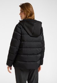 Giacca a vento nera con cappuccio, caratterizzata da sezioni trapuntate, texture liscia e taglio comodo. Progettata per calore e comfort.