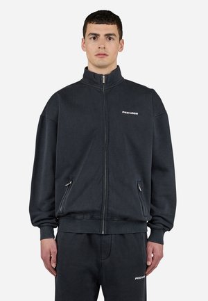 Mørkegrå lynlås-sweatshirt med høj krave, ribbede manchetter og to forreste lynlås-lommer. Har hvidt "PEGAADOR" logo på brystet.