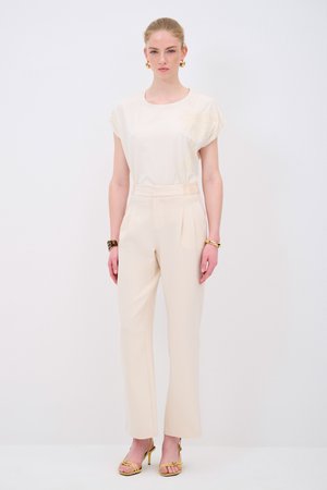 Beige top s květinovou výšivkou, světlé vysoké kalhoty a žluté lodičky na řemínky. Hladká textura, přizpůsobený střih, minimalistický design.