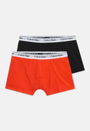 Een paar Calvin Klein herenshortjes, één in effen zwart en één in effen rood, beide met een witte gebrande tailleband.
