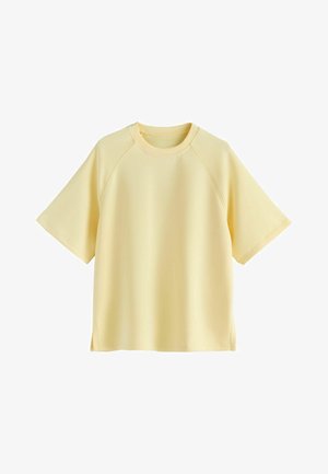 Bladożółty bawełniany t-shirt z krótkim rękawem, okrągłym dekoltem, rękawami raglanowymi i bocznymi rozcięciami.