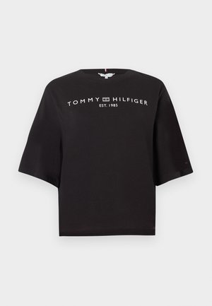 Camiseta negra de Tommy Hilfiger con mangas anchas y texto de logo blanco "TOMMY HILFIGER EST. 1985" en el pecho.
