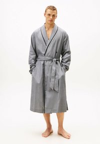 Albornoz a rayas grises con cuello tipo chal, cinturón para atar y bolsillos laterales. La tela tiene una textura suave, con detalles en negro a lo largo del cuello.